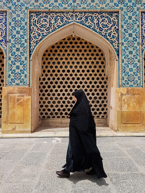 Frau, die einen schwarzen Hiqab in einer muslimischen Moscheetür im Iran trägt