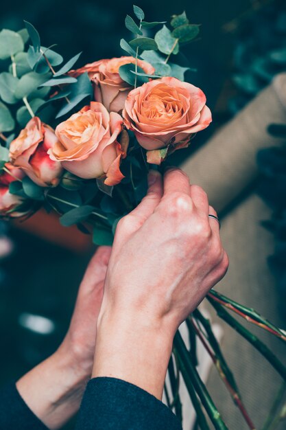 Frau, die einen Strauß roter Rosen vorbereitet