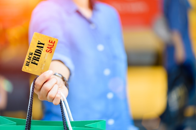 Frau, die Einkaufstaschen und Kreditkarte im Supermarkt hält. Black Friday-Konzept.