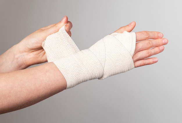 Foto frau, die elastische bandage um schmerzhaftes handgelenk wickelt kompressionswickel muskelverstauchungen zerren behandlung armtrauma gesundheitskonzept