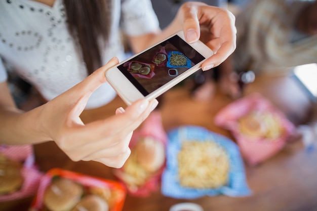 Frau, die Essen durch Handy im Restaurant fotografiert