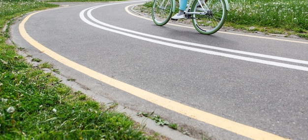 Frau, die Fahrrad auf Radweg mit Markierungen im Park fährt