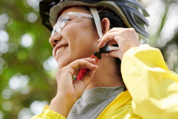 Frau, die Fahrradhelm befestigt