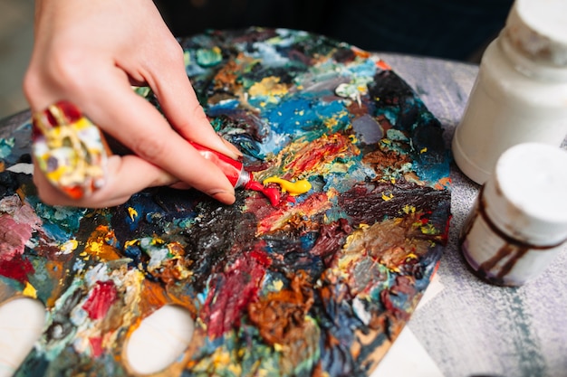 Frau, die Farben auf Palette im Kunststudio mischt