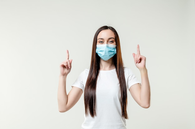 Foto frau, die finger auf kopierraum zeigt, der maske trägt