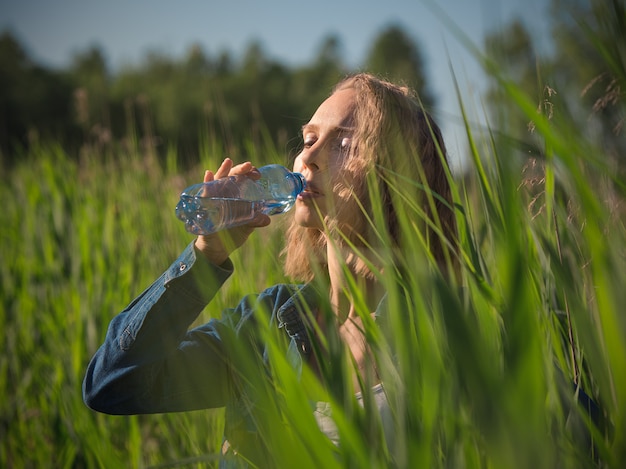 Frau, die Flasche Wasser an einem heißen Sommertag trinkt