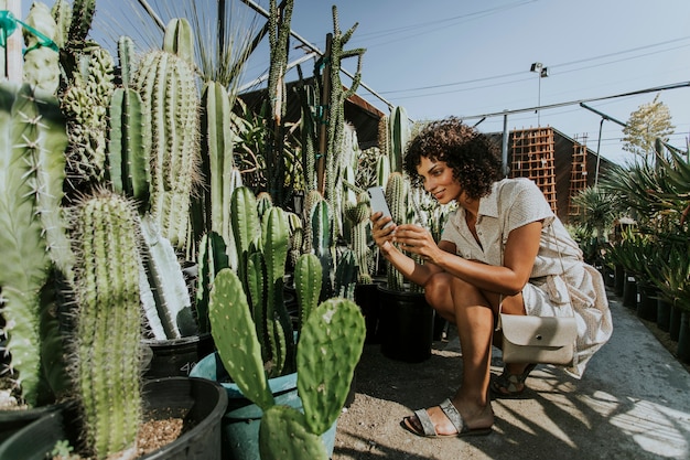 Frau, die Fotos von Kakteen in einem botanischen Garten macht