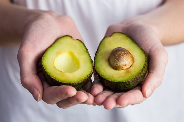 Frau, die frische Avocado zeigt