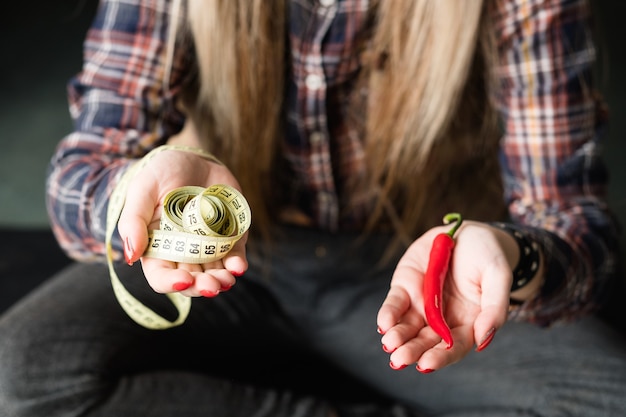 Frau, die frischen Chilipfeffer mit verdrehtem Maßband in der Hand hält.