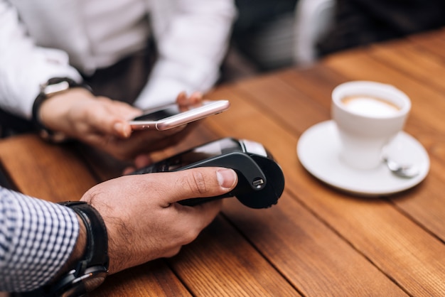 Frau, die für Kaffee durch Handy im Restaurant zahlt.