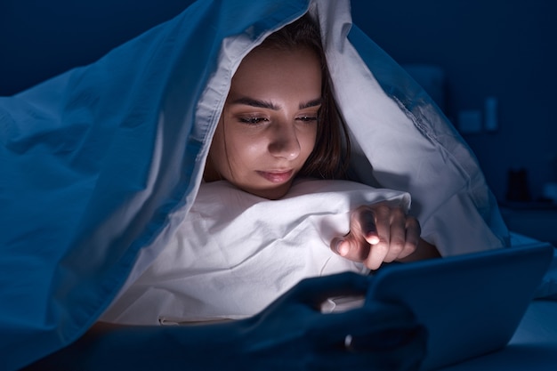 Frau, die Gadget im Bett benutzt