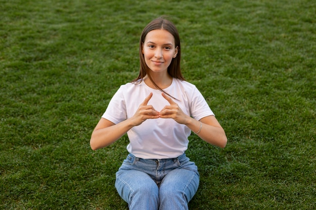 Foto frau, die gebärdensprache draußen auf gras verwendet