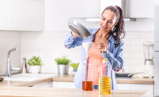 Frau, die gebrauchtes Speiseöl zum Recycling und zur Wiederverwendung in die Plastikflasche gießt.