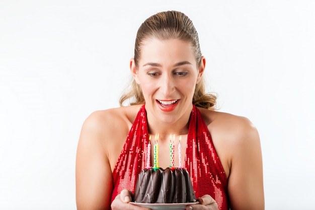 Frau, die Geburtstag mit Kuchen und Kerzen feiert