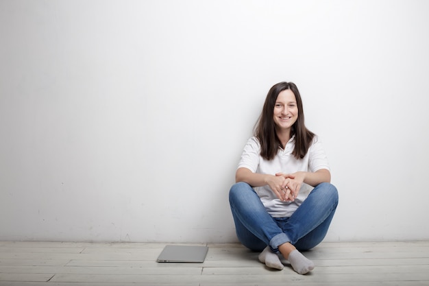 Frau, die gegen die Wand auf dem Boden sitzt