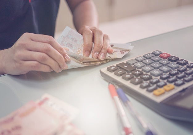 Frau, die Geld auf Tabelle im Büro zählt.