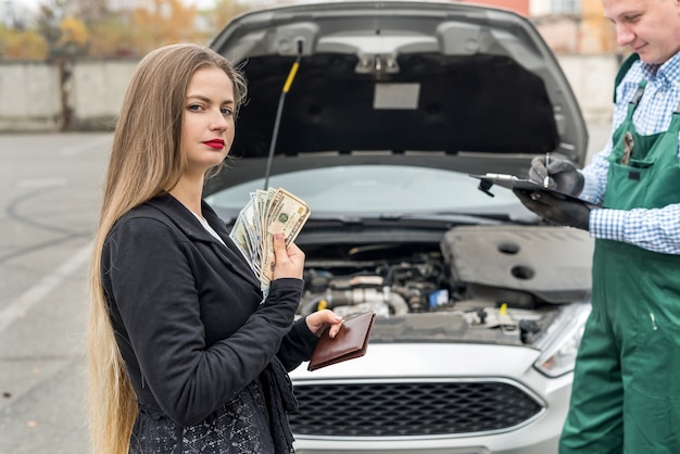 Frau, die Geld zählt, um für Autoservice zu bezahlen