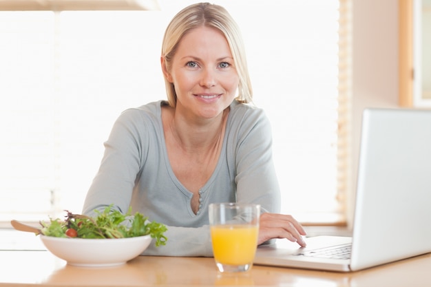 Frau, die gesund beim Arbeiten an ihrem Notizbuch zu Mittag isst