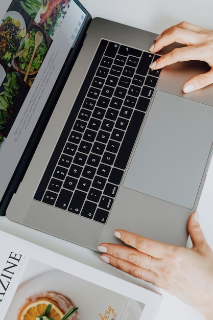 Frau, die gesunde vegetarische Rezepte auf ihrem Laptop betrachtet