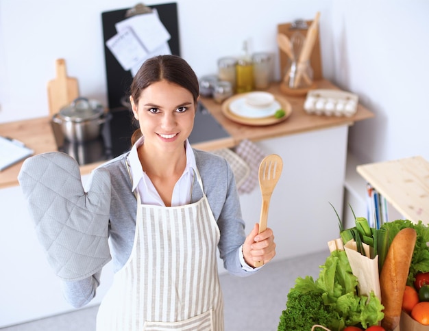 Frau, die gesundes Essen macht, steht lächelnd in der Küche