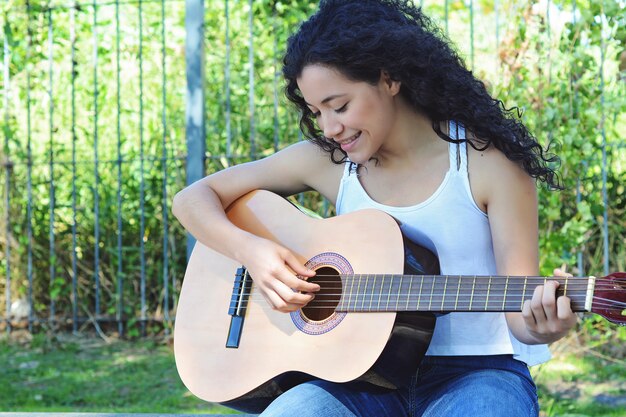 Frau, die Gitarre am Park spielt.