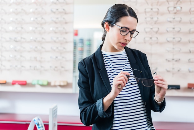 Frau, die Gläser vom Regal im Optikergeschäft entfernt