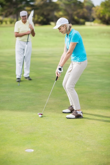 Frau, die Golf spielt, während sie durch Mann steht