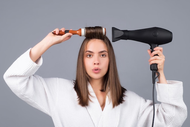 Frau, die Haare kämmt Porträt des weiblichen Modells mit Haartrockner Mädchen mit Haarbürste Haarpflege und Schönheit Morgenroutine