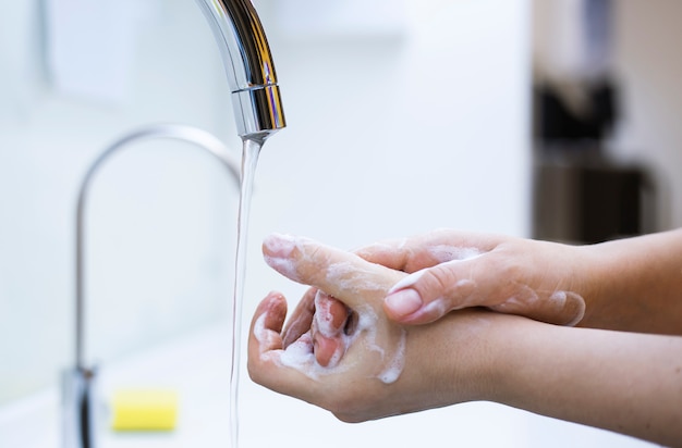 Frau, die Hände unter dem Wasserhahn wäscht. Hygienekonzept Hand Detail.