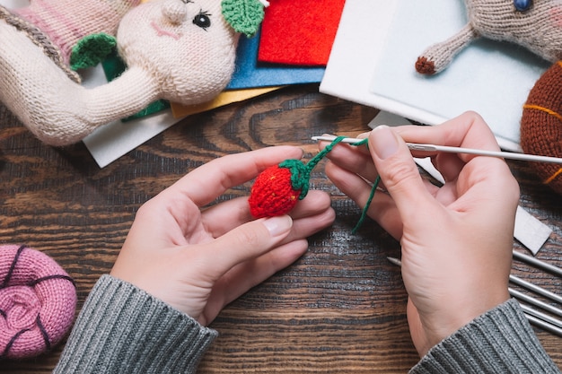 Foto frau, die handgemachte gestrickte weihnachtsspielzeuge macht