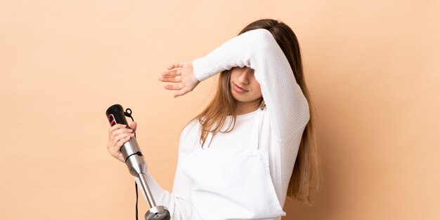 Frau, die Handmixer über isolierten Wandbedeckungsaugen durch Hände verwendet