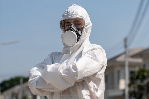 Frau, die Handschuhe mit chemischem Schutzanzug und Maske der biologischen Gefahr trägt. Sie verschränkte die Arme mit unglücklichem Gesicht.