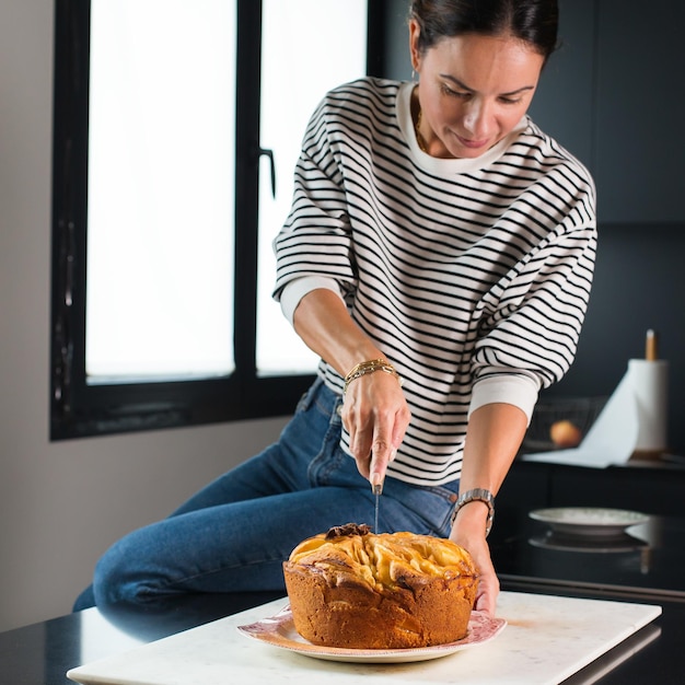 Foto frau, die hausgemachten apfelkuchen in der küche schneidet