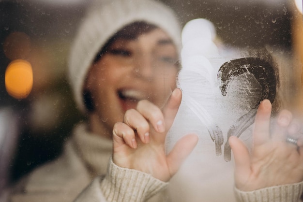 Foto frau, die herz auf das fenster zeichnet