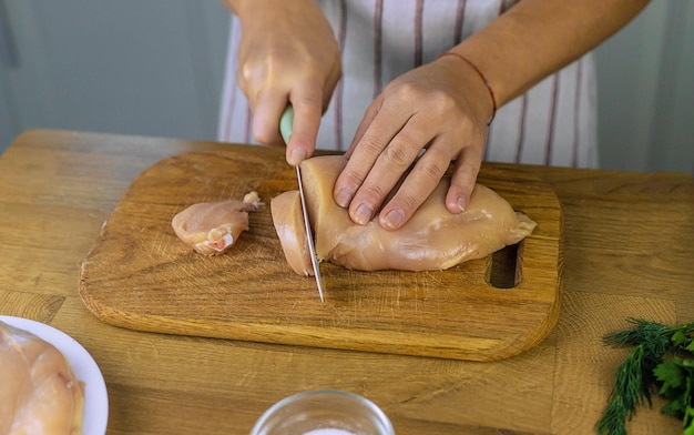 Frau, die Hühnerfleisch selektiven Fokus einlegt