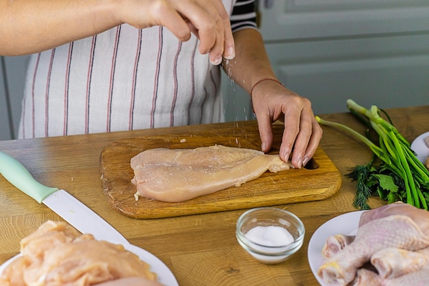 Frau, die Hühnerfleisch selektiven Fokus einlegt