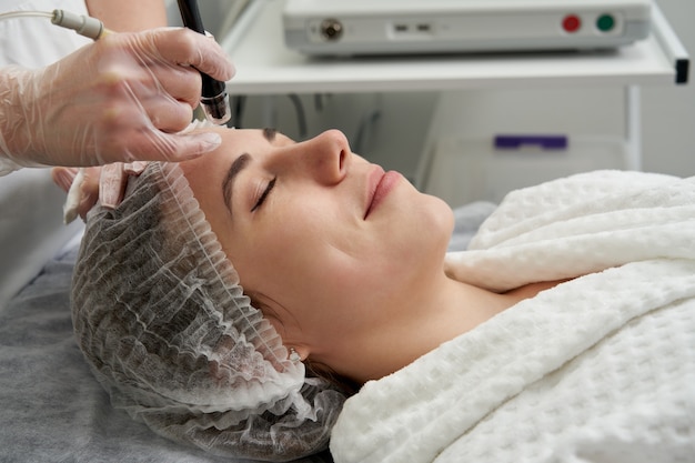 Frau, die hydro hydrodermabrasion peeling-behandlung im gesicht bei cosmetic beauty spa clinic erhält. hydra