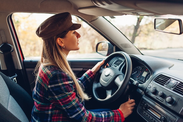 Frau, die ihr Auto startet. Junger Fahrer fügt Schlüssel in die Zündung ein, die bereit ist zu gehen. Der Besitzer schaltet sich automatisch ein