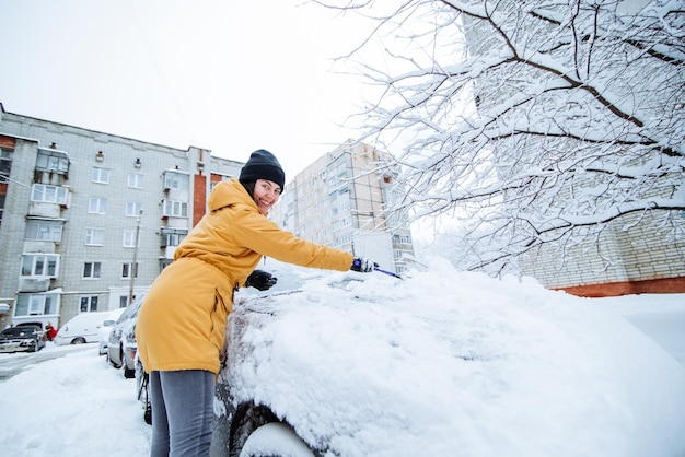 Frau, die ihr Auto von Schnee nach Schneesturm säubert