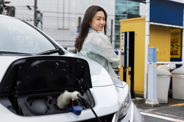 Frau, die ihr Elektroauto an der Station auflädt