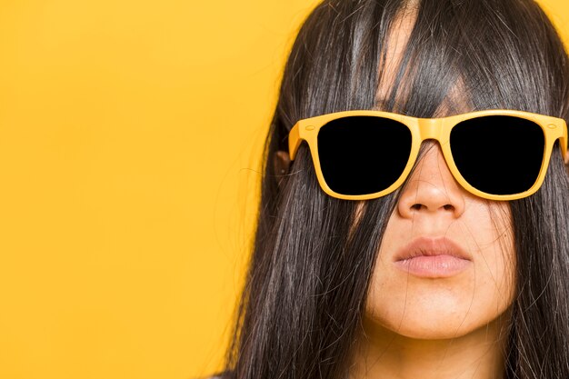 Frau, die ihr Gesicht mit dem Haar und Sonnenbrille bedeckt