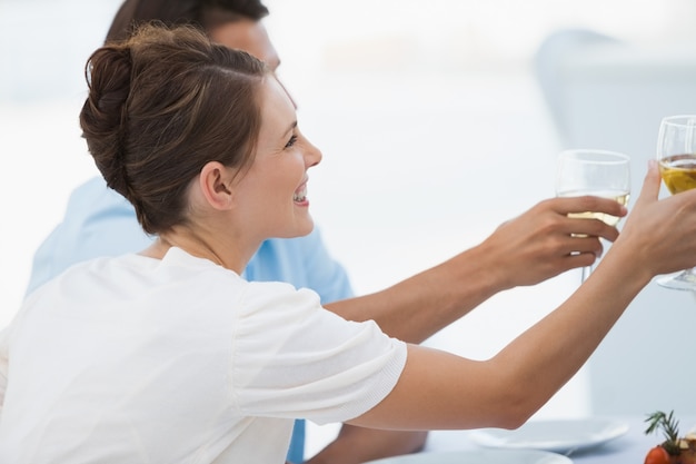 Frau, die ihr Glas Weißwein mit Leuten klirrt