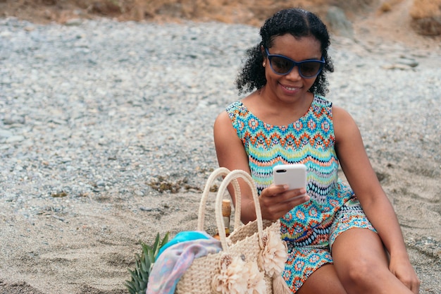 Frau, die ihr Handy am Strand überprüft