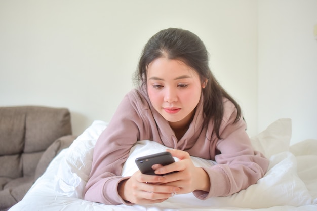 Frau, die ihr Handy im Bett benutzt