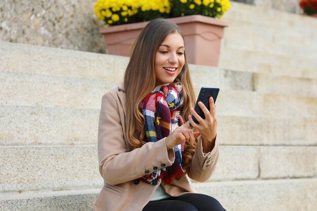 Frau, die ihr Telefon beim Gehen in der Stadt benutzt