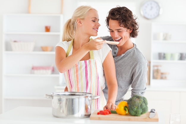 Frau, die ihr Verlobtes ihre Mahlzeit schmeckend macht