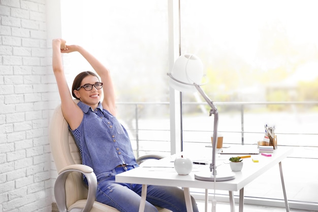 Frau, die ihre Arme im Büro ausdehnt