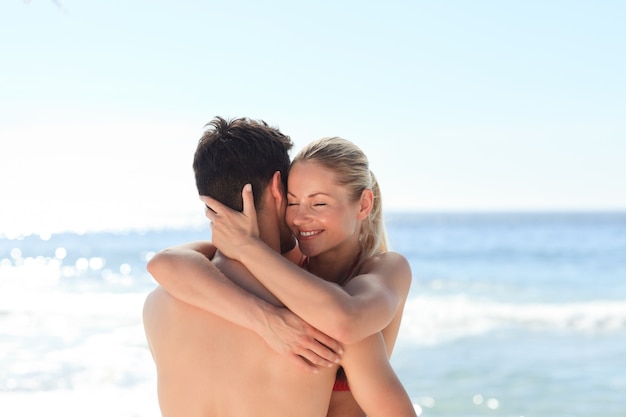 Frau, die ihren Freund am Strand umarmt