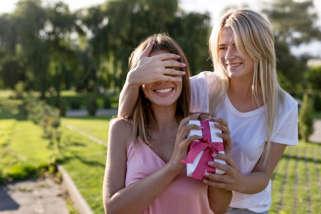 Foto frau, die ihren freund mit einem geschenk überrascht