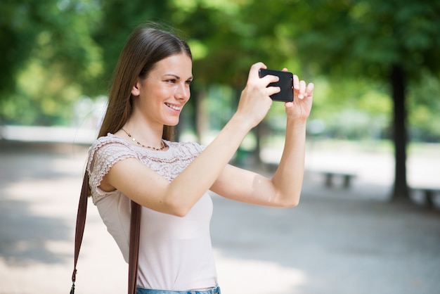 Frau, die ihren Handy verwendet, um ein Foto zu machen